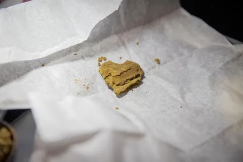 Close-up of a Piece of Hashish inside a white paper wrapper. Stock Photos