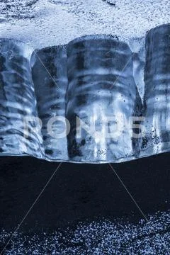 Close-up of a piece of ice sitting in the black sand on the South shore of Icela Stock Photos