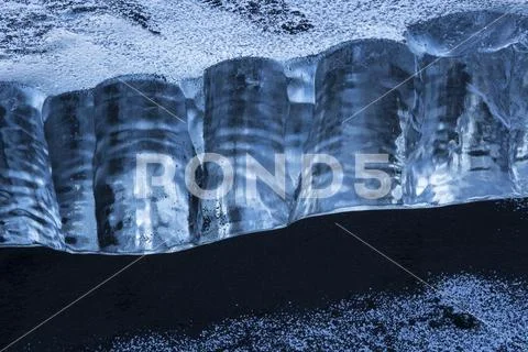 Close-up of a piece of ice sitting in the black sand on the South shore of Icela Stock Photos