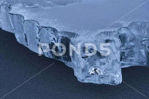 Close-up of a piece of ice sitting in the black sand on the South shore of Icela Stock Photos