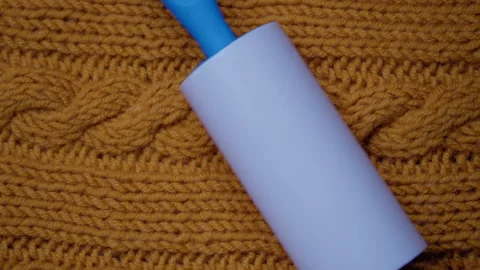 Close up on piece knitted wool fabric spend roller for cleaning clothes. Roller Stock Footage 138877093