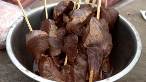 Close-up of pieces of beef heart meat on wooden sticks for anticuchos on grill Stock Footage 160087597
