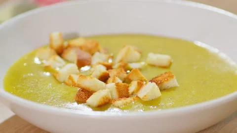 In a close up, pieces of dried white bread fall into the thick soup. Video stock 235695068