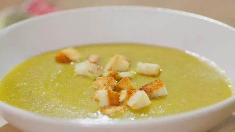 Close up of pieces of dried white bread falling into the cream soup. Video stock 237098432