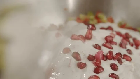 Close-up pieces of pomegranate are thrown into metal bowl with salad. Slow Video stock 113607574