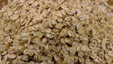 Close up, Pile Dry Oat Flakes Slowly Rotate on a Wooden Plate or Cutting Board Stock Footage 237713501