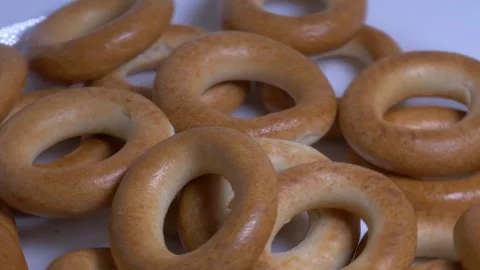 Close-up of a pile of small ring-shaped bread rolls rotating on a white pla.. Stock Footage 340070582