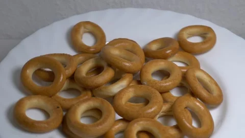 Close-up of a pile of small ring-shaped bread rolls rotating on a white pla.. Stock Footage 340070630