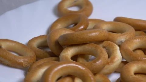 Close-up of a pile of small ring-shaped bread rolls rotating on a white pla.. Stock Footage 340070633