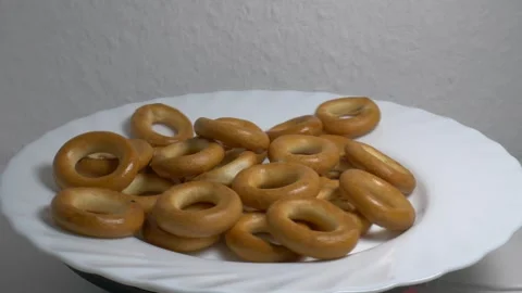 Close-up of a pile of small ring-shaped bread rolls rotating on a white pla.. Stock Footage 340070730