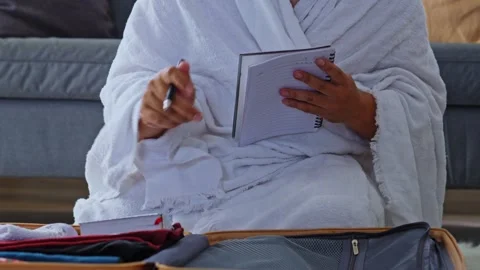 Close-up of pilgrim in Ihram robe using pen and notepad to plan religious Stock Footage 328265667