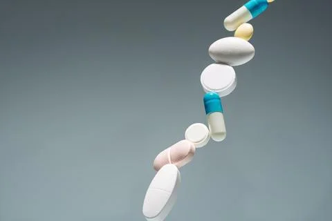 Close-up: pills and capsules stack in midair on gray background with copy s.. Stock Photos