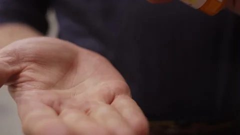 Close-up of a pills getting poured in a man's hand, he takes them Video stock 127220427