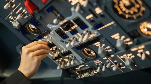Close-up of a pilot's hand turning a toggle switch on the control panel. Stock Photos