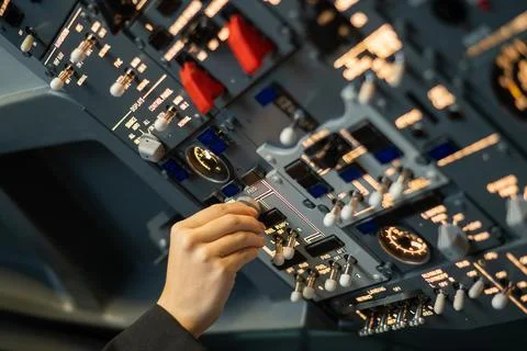Close-up of a pilot's hand turning a toggle switch on the control panel. Stock Photos