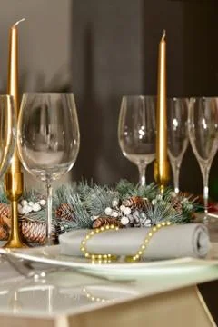 Close up of a pine-cone wreath surrounded by glasses and candles on a table Stock Photos