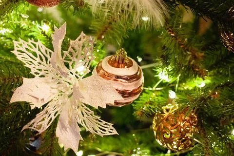 Close-up of pine tree branches, white snowflake, rose-gold bauble and lights. Foto stock