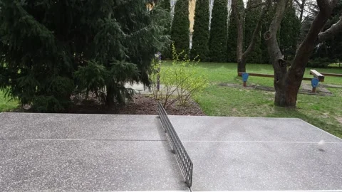 Close-up of a ping pong ball in mid-air over a concrete table tennis Vidéo 328420521