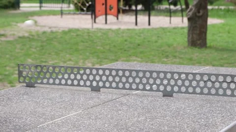 Close-up of a ping pong ball in mid-air over a concrete table tennis table Stock Footage 328421032