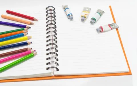 Close-up of pink orange note book and colored pencils, water colors Stock Photos