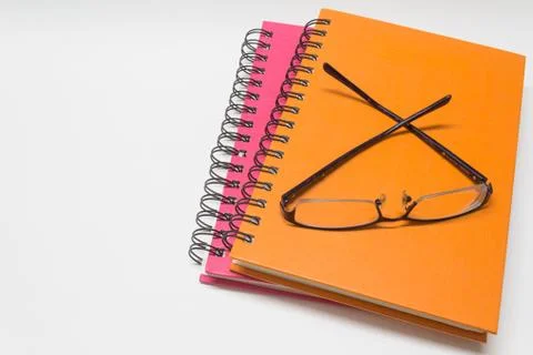 Close-up of pink orange note book and eye-glasses Stock Photos