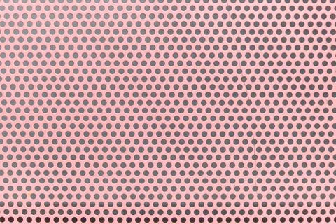 Close-up of pink perforated pattern with dark dots Stock Photos