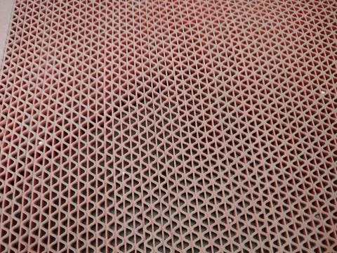 Close-up of a pink plastic mesh grid showing repeating triangular openings .. Stock Photos