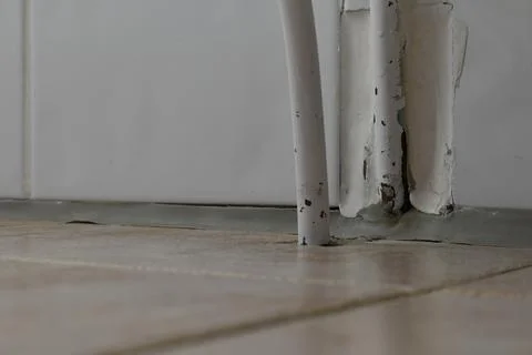 Close-Up of a Pipe and Peeling Paint on Floor Stock Photos