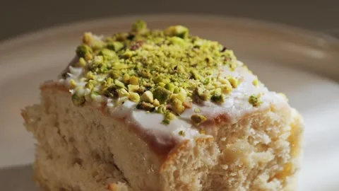 Close-up of pistachio cake slice topped with cream frosting and crushed Stock Footage 336060293