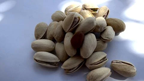 Close-up of pistachio nuts in shells with a single almond placed in the center Stock Photos