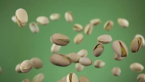 Close up of pistachios bouncing on the olive green background Stock Footage 133925149