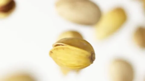 Close up of pistachios flying up on the white background in slow motion Vídeo Stock 148553711