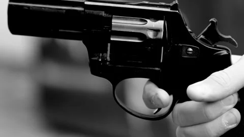 Close-up of a pistol in a hand pulling the trigger and firing a shot Stock Footage 320604558