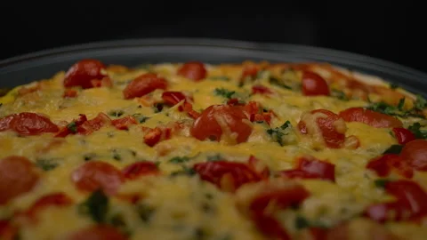 Close-up, pizza with cheese and tomatoes in a turning motion on a black Stock Footage 201806942