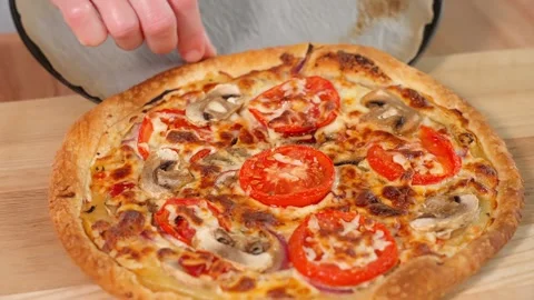 Close-up of a pizza maker placing hot pizza on a wooden board Stock Footage 257698176