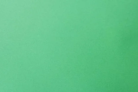 A close-up of a plain green paper surface with a subtle texture. Stock Photos