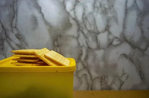 A close up of plain, rectangular crackers neatly stacked in a vibrant yello.. Foto stock
