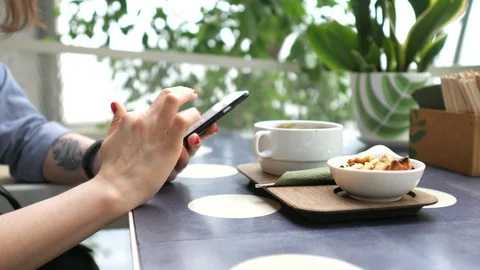 Close plan, female hands are holding a smartphone in a cafe at lunch Stock Footage 100144350