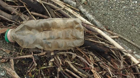 Close-up of a plastic bottle on the beach as the camera pans from left to Stockbeeldmateriaal 102297522