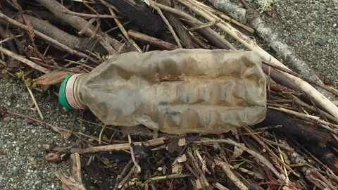 A close-up of a plastic bottle on the beach. Stockbeeldmateriaal 102297542