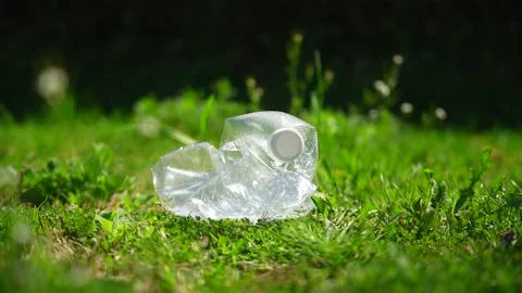 Close up of a plastic bottle on a green grass lawn in a public park Stock Footage 236877460
