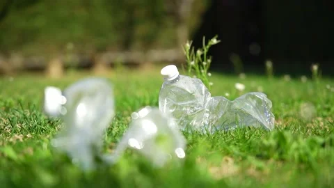 Close up of a plastic bottle on a green grass lawn in a public park Vídeo Stock 236901028