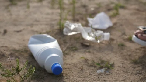 Close-up. A plastic bottle lies on the ground, a female hand in a glove picks it 库存影片 117845630