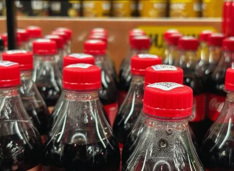 Close up of plastic bottle necks with red caps filled with dark soda drink .. Stock Photos