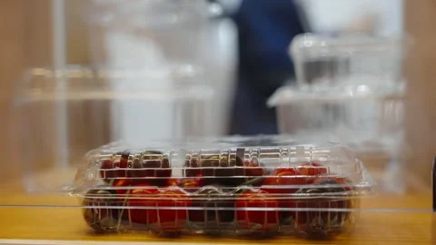 Close-up of plastic clamshell packaged cherry tomatoes on a wooden counter with Video stock 325672060