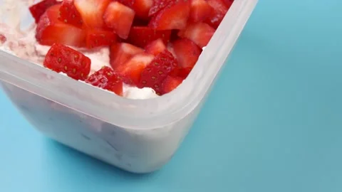 Close-up of a plastic container with cottage cheese and strawberries Stock Footage 150898765
