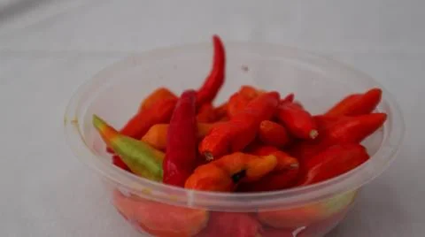 : A close-up of a plastic container filled with vibrant red and green chili.. Stock Photos
