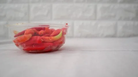 : A close-up of a plastic container filled with vibrant red and green chili.. Stock Photos