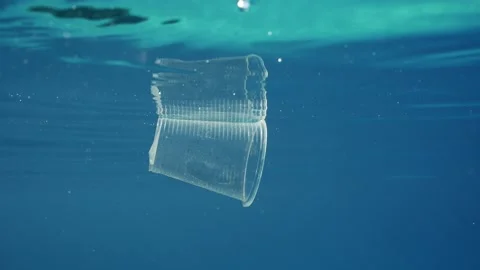 Close-up of plastic cup floating underwater, Plastic pollution of Ocean, Slow Stock Footage 243443559