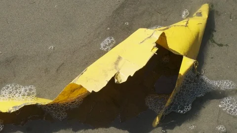 Close-up of plastic garbage imbedded in the sand at the beach. Bubbles can Stockbeeldmateriaal 118576282